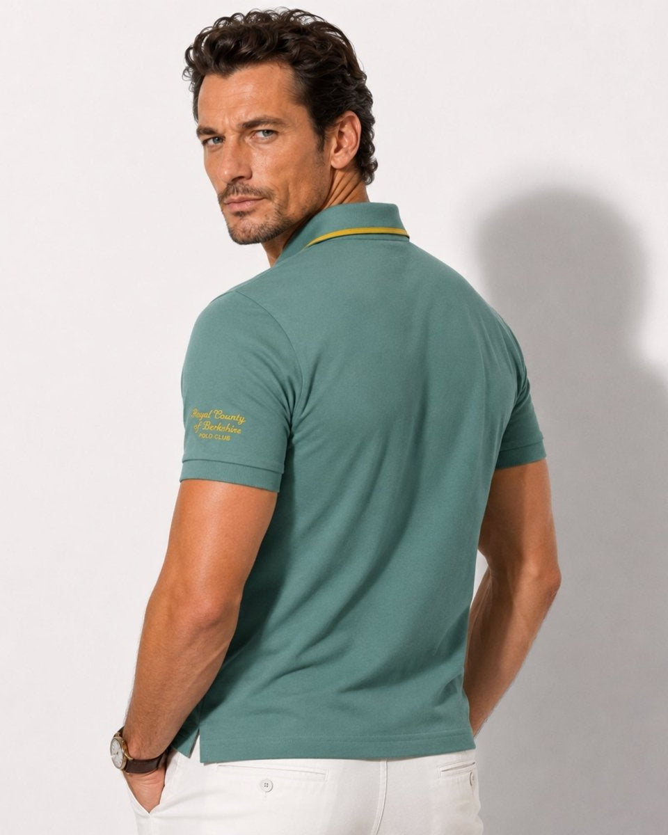 Man wearing a green polo shirt with a visible brand logo on a white background
