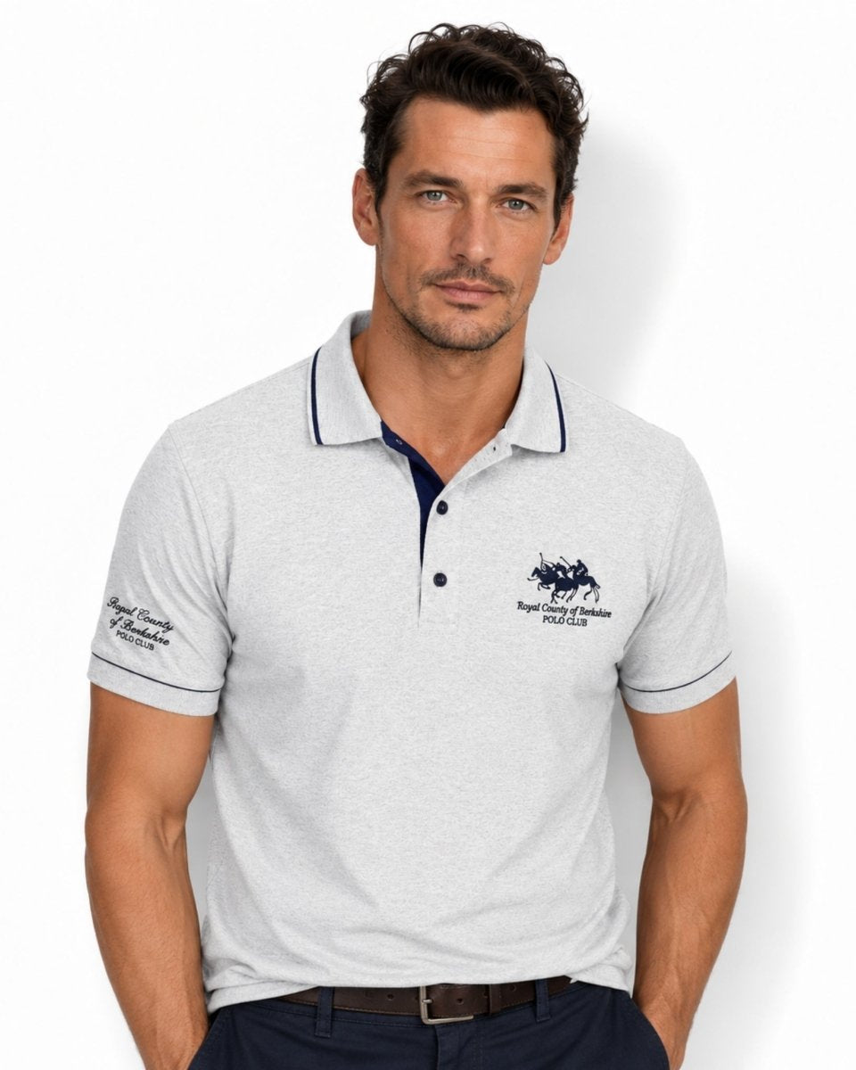Man wearing a light gray polo shirt with brand logos on a white background