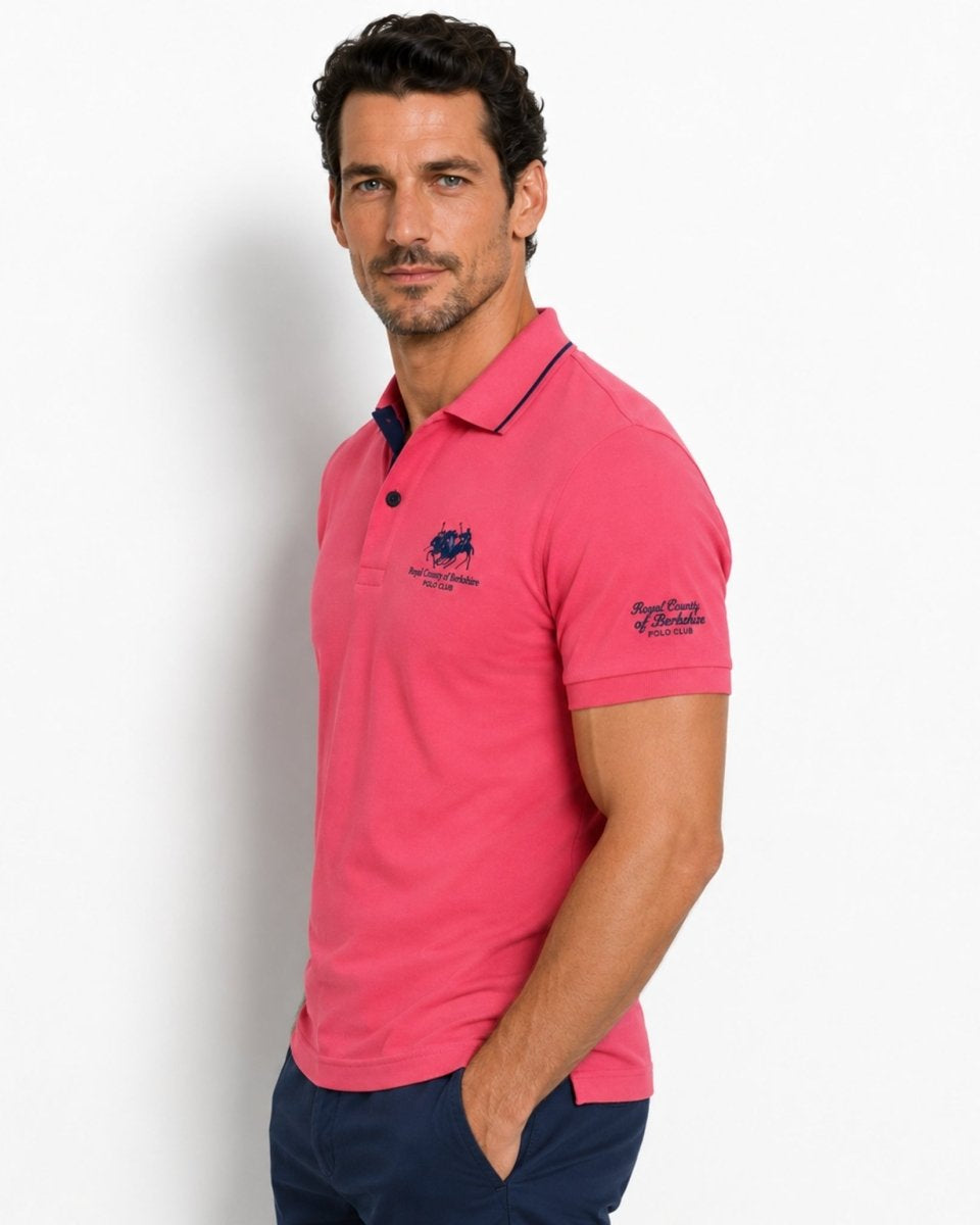 Man wearing a pink polo shirt with a brand logo on a white background