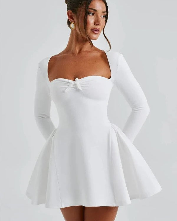 Woman wearing a white dress with long sleeves on a plain background