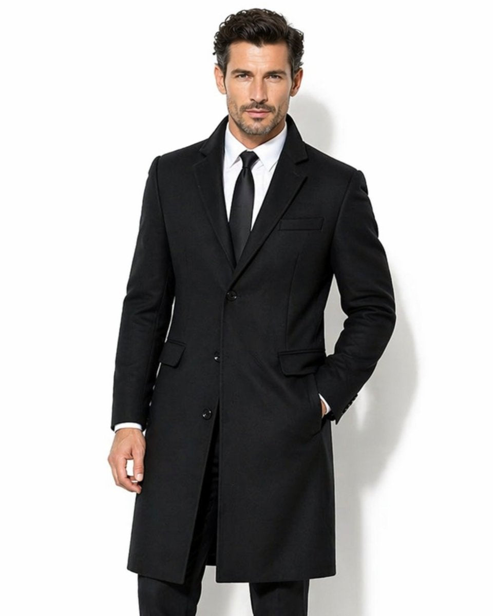 Front view of men's black single-breasted tailored wool overcoat, featuring a classic notch lapel and flap pockets over a white shirt and black tie.