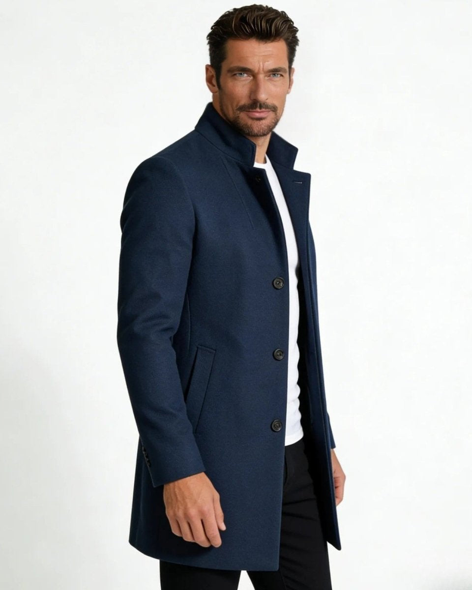Side profile view of a man in a slim-fit blue wool winter topcoat with a stand-up funnel neck collar.