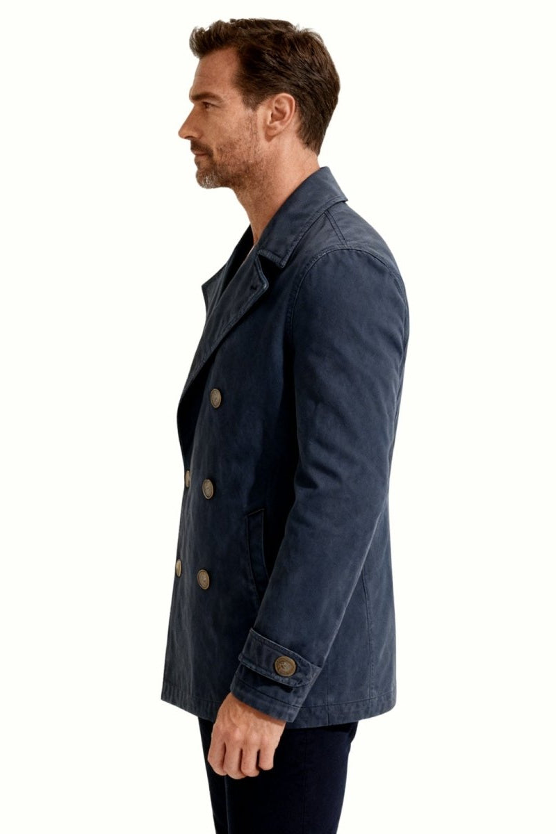 Side profile view of a man wearing the  navy blue double-breasted cotton peacoat to show its length and silhouette.