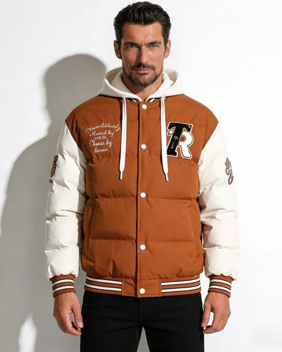 Model wearing the men's cognac camel hooded puffer varsity jacket, showing the 'R' chenille patch and snap button front