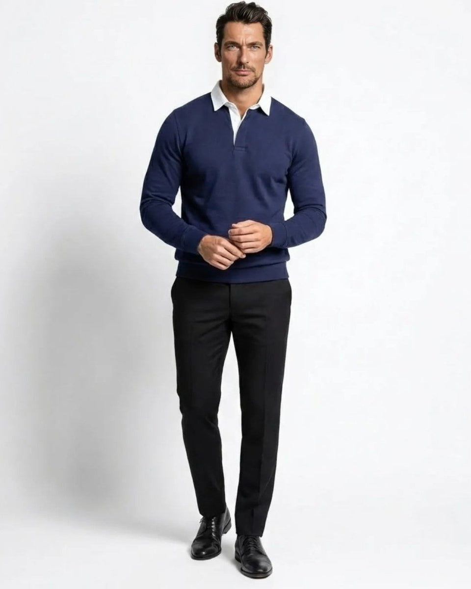 Model wearing the men's navy blue knit long sleeve polo sweater with black trousers, showing the tailored fit and white contrast collar.