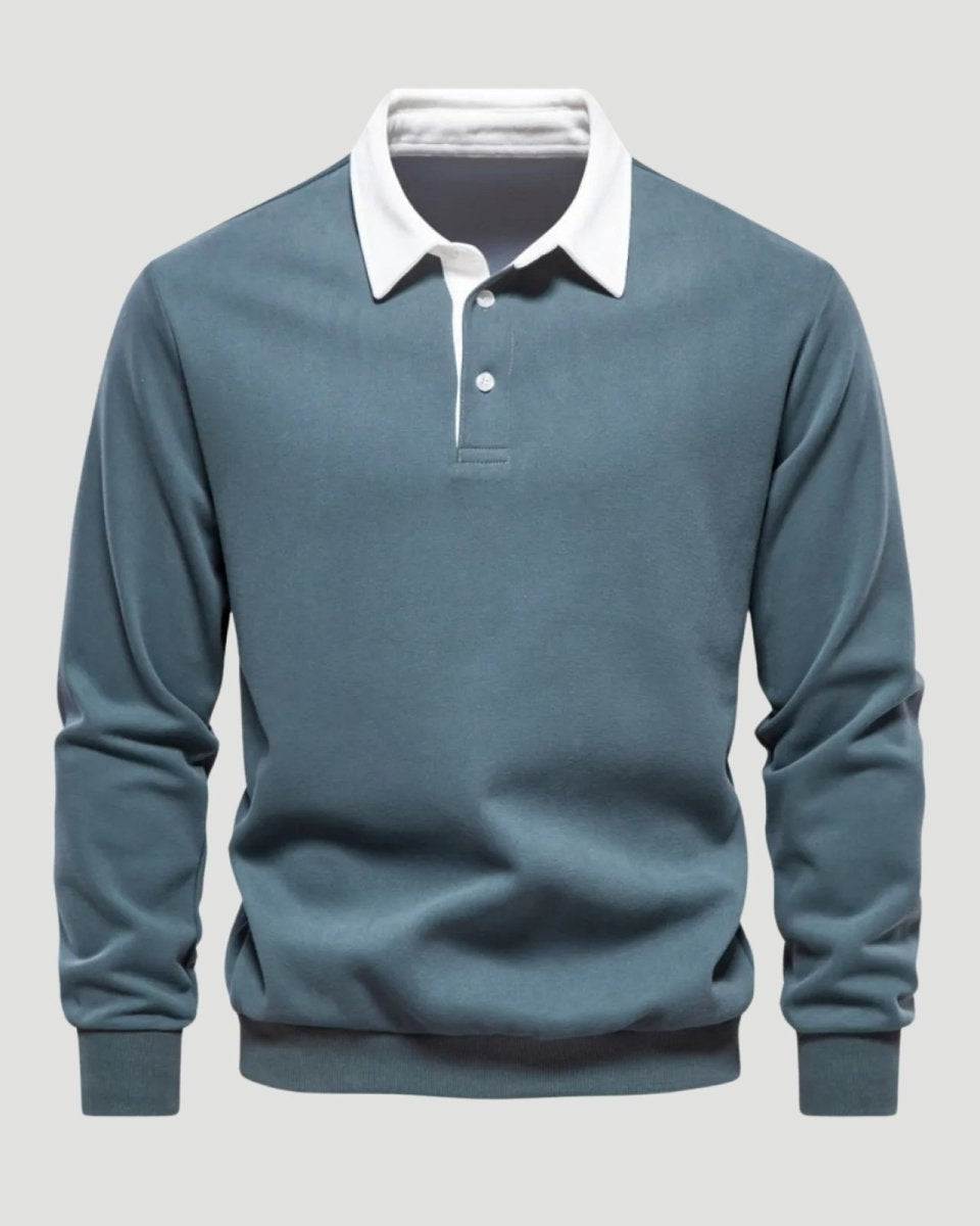 Flatlay studio shot of the front of a men's grey blue polo sweatshirt, detailing the three-button placket and white contrast collar.