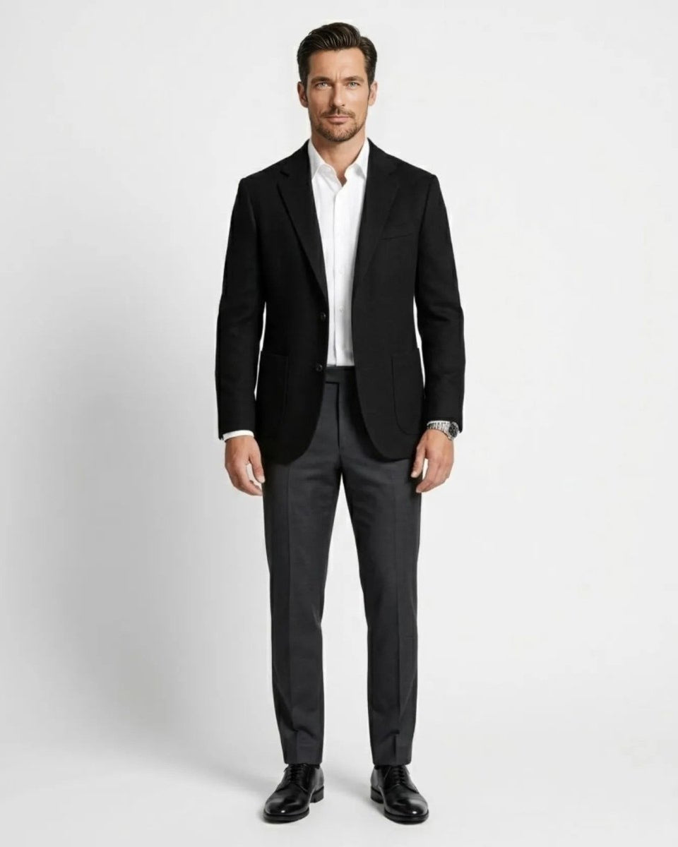 Full body look of men's black smart casual blazer styled with charcoal grey trousers and black dress shoes.