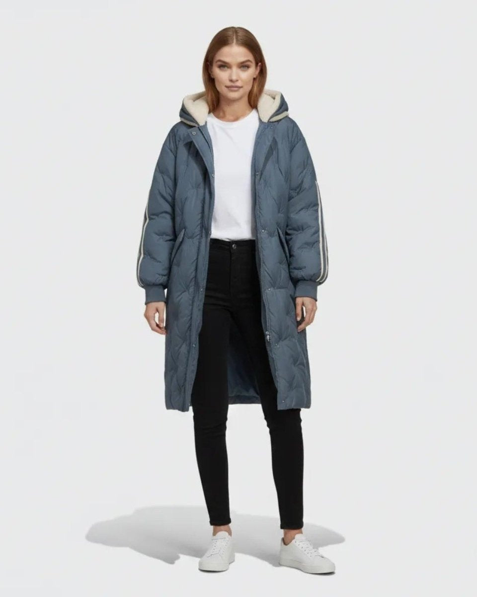 Woman wearing the Meridian long quilted down parka in slate dark blue with a sherpa-lined hood, front view.
