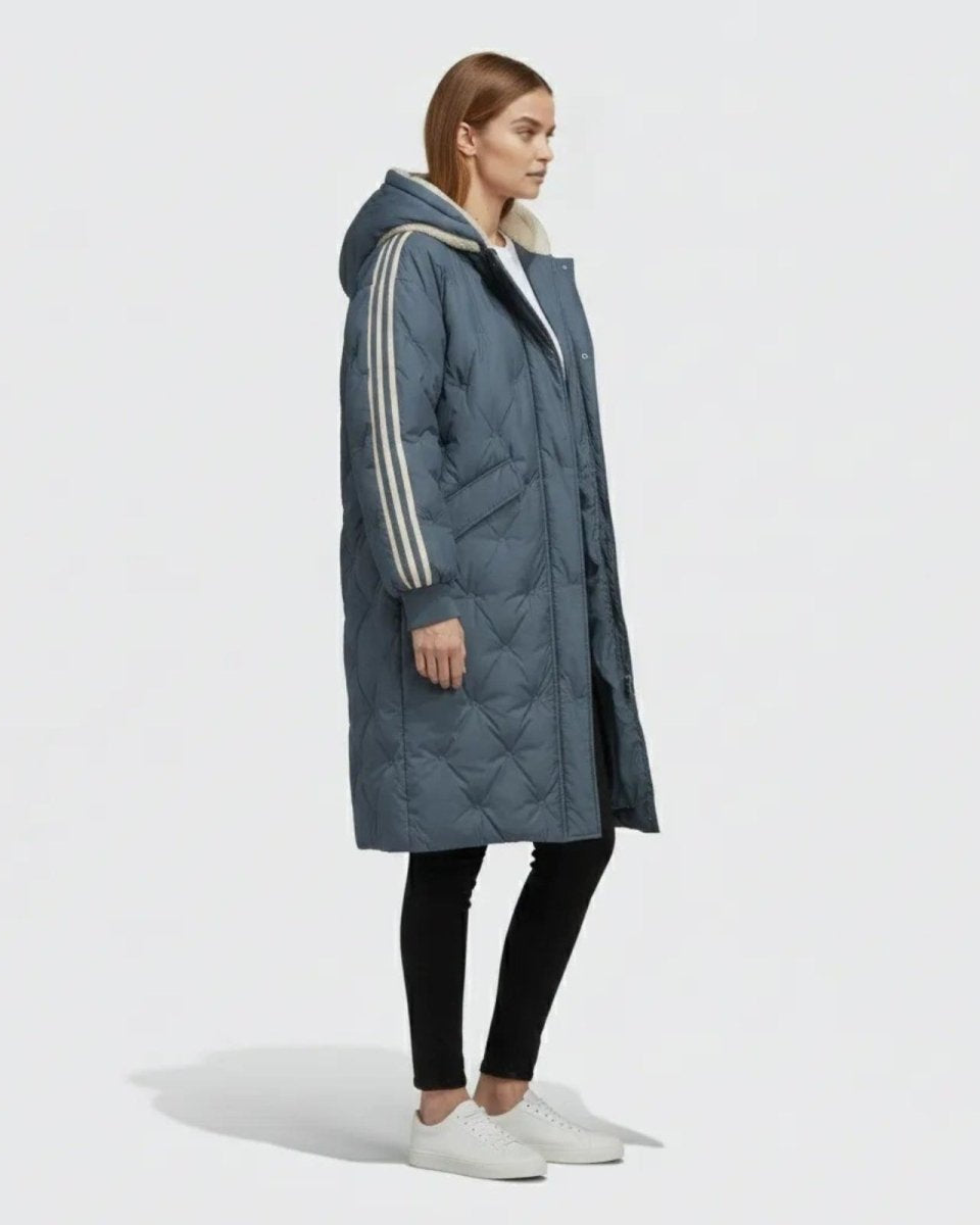 Side profile of a woman in the Meridian slate dark blue parka, showing the knee-length cut and stripe detail on the sleeve.