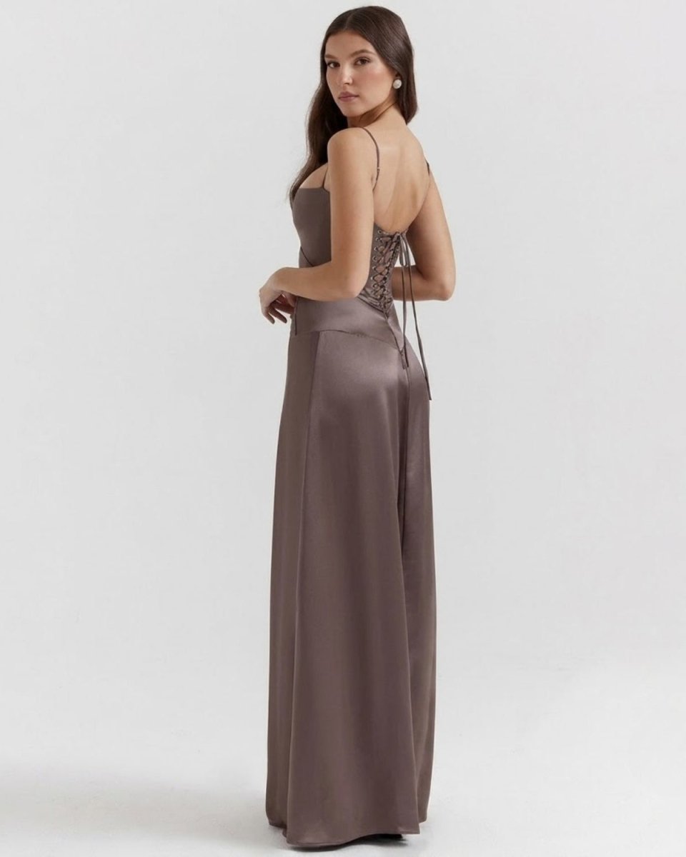 A woman modeling a floor-length satin gown in a taupe-brown color, shown from the back three-quarter view against a light gray studio background.