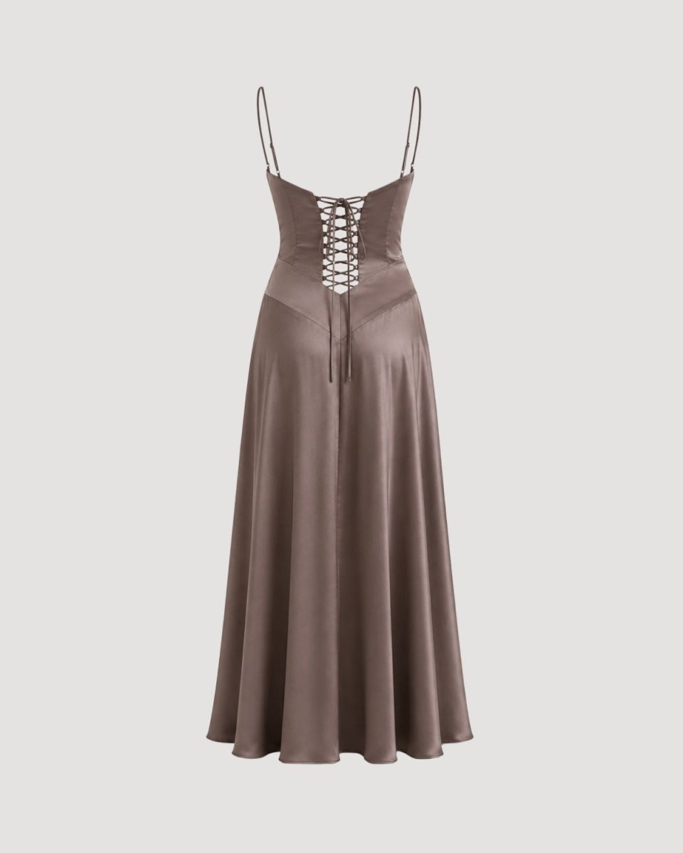 A floor-length satin slip dress in a muted taupe-brown color, featuring thin spaghetti straps, a sweetheart neckline, and a lace-up corset-style bodice with a tie-front closure, shown against a solid light gray background.