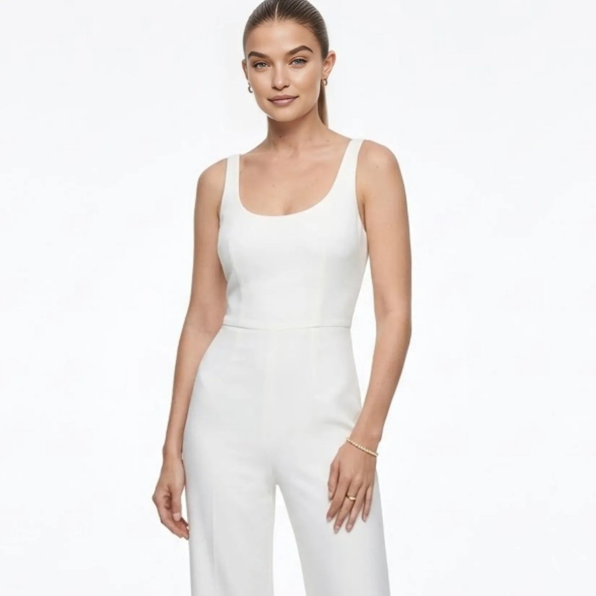  Full body shot of a model in a stylish white jumpsuit, accessorized with the Kouvr gold stretch tennis bracelet for an elegant look.
