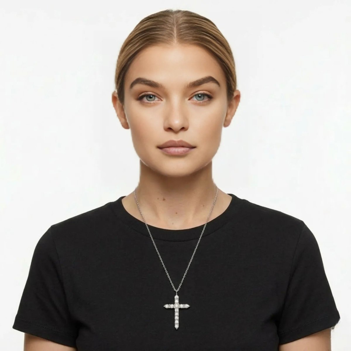 A model wearing the Kouvr silver-tone pave cross necklace layered over a simple black crewneck t-shirt.
