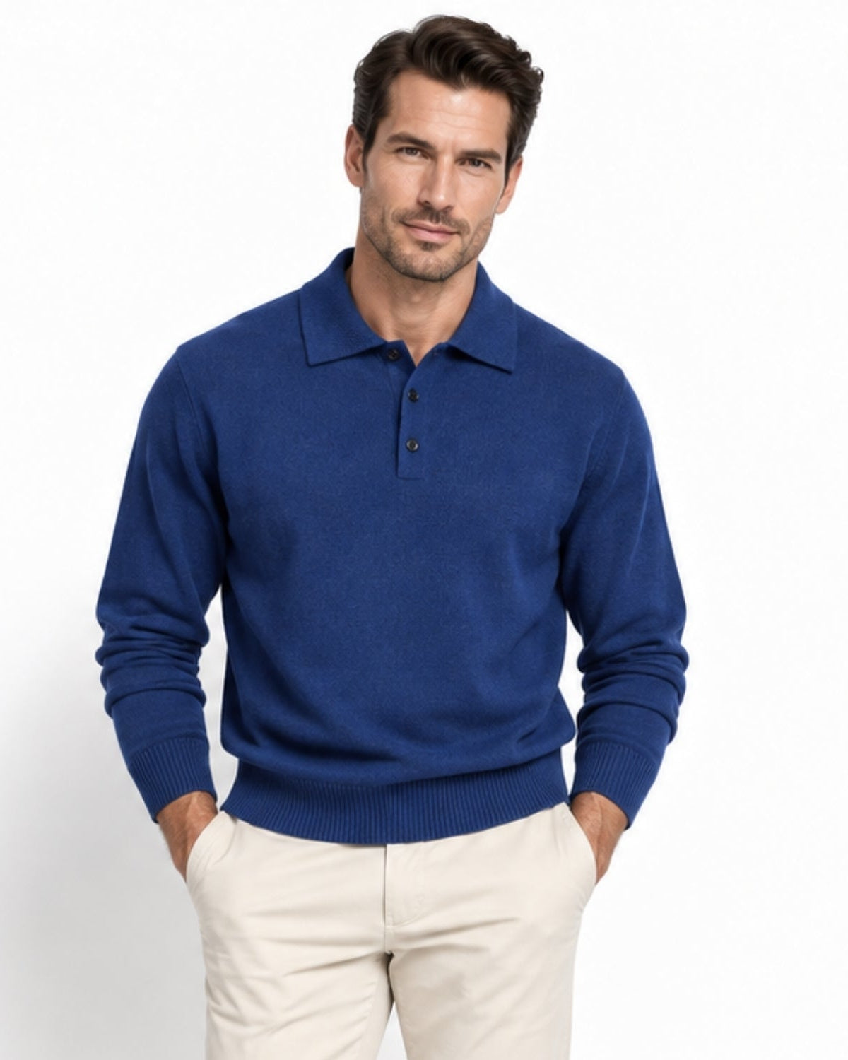 A man wearing a navy knit polo sweater and light beige trousers, standing against a plain white studio background.