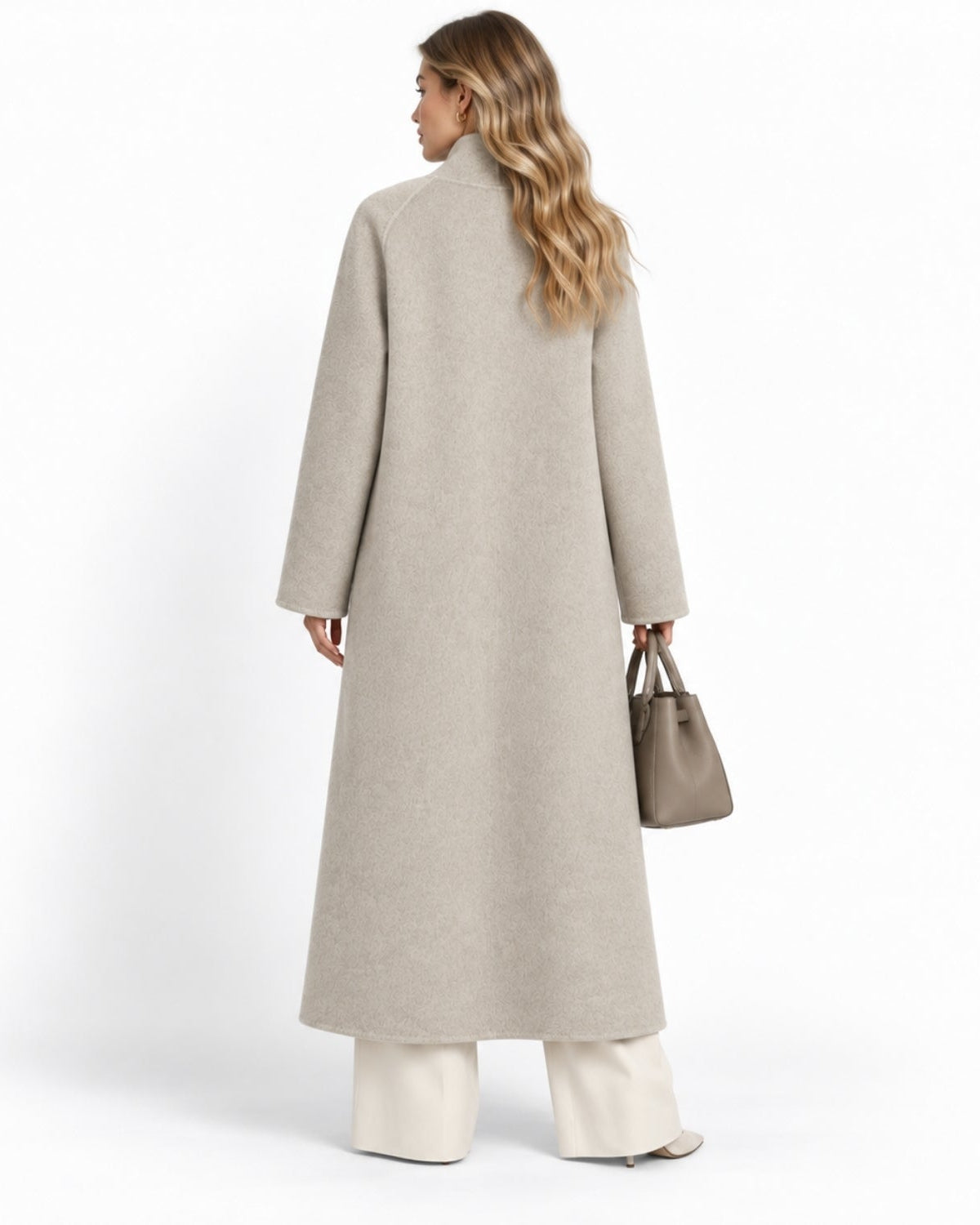 A woman shown from the back wearing a long, light beige wool coat, white wide-leg trousers, and holding a taupe leather handbag against a clean white studio background.