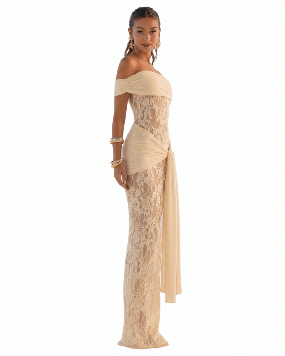 A woman modeling an off-the-shoulder champagne lace gown with a draped waist detail, shown against a plain white background.