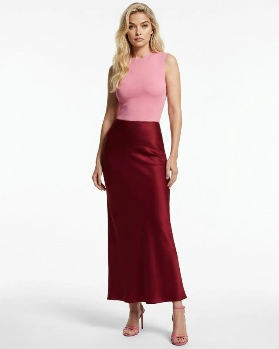 Model wearing The Ourania, a high-waisted red satin maxi skirt, paired with a pink top