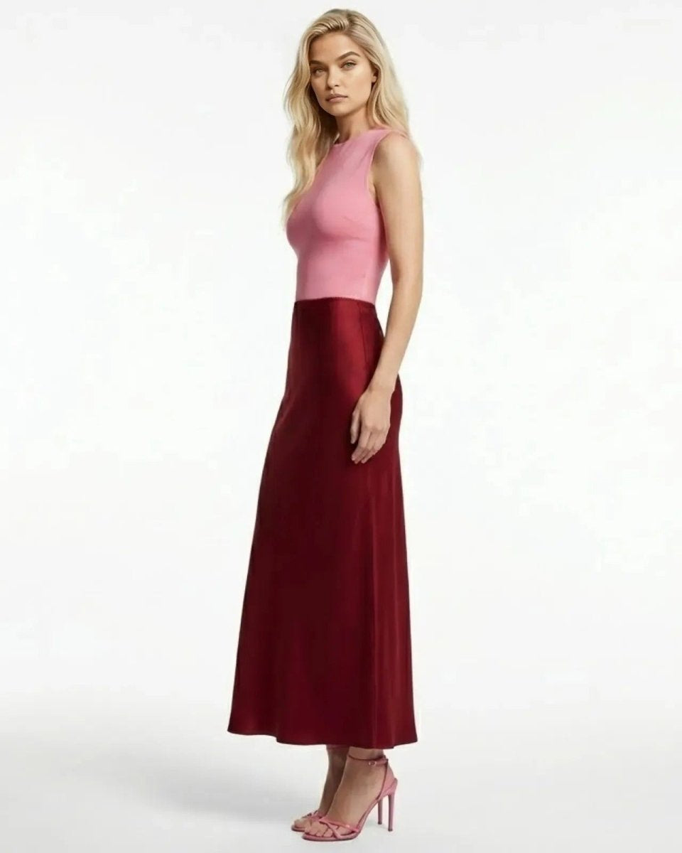 Side profile view of a woman wearing a long, wine-red satin slip skirt showing its elegant drape and ankle length.