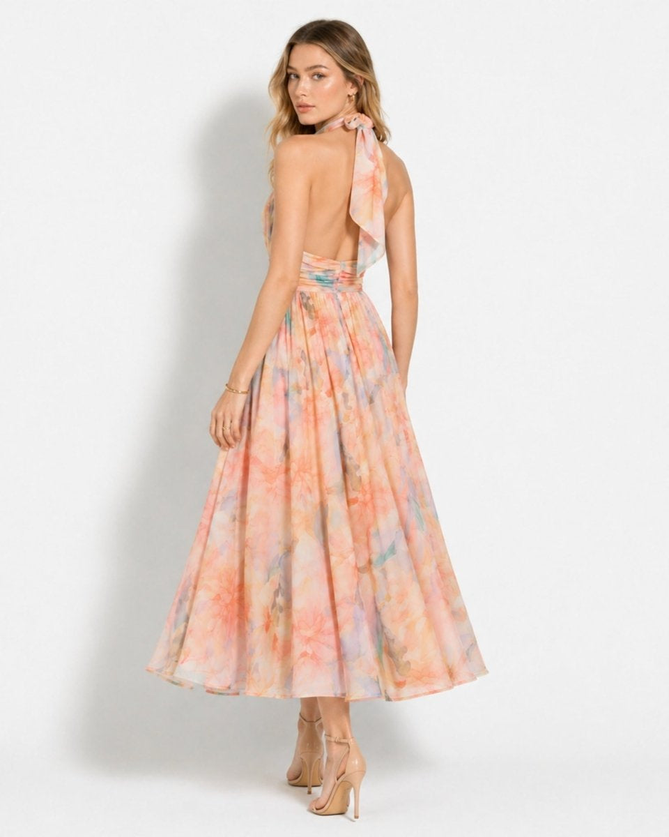 Back view of woman showing the open back and neck tie detail of the floral halter dress