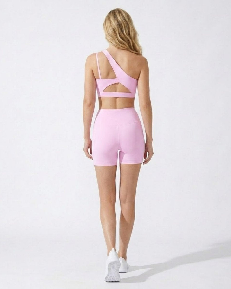 Back view of women's matching pink gym set showing the sports bra's elegant back cutout detail and form-fitting biker shorts