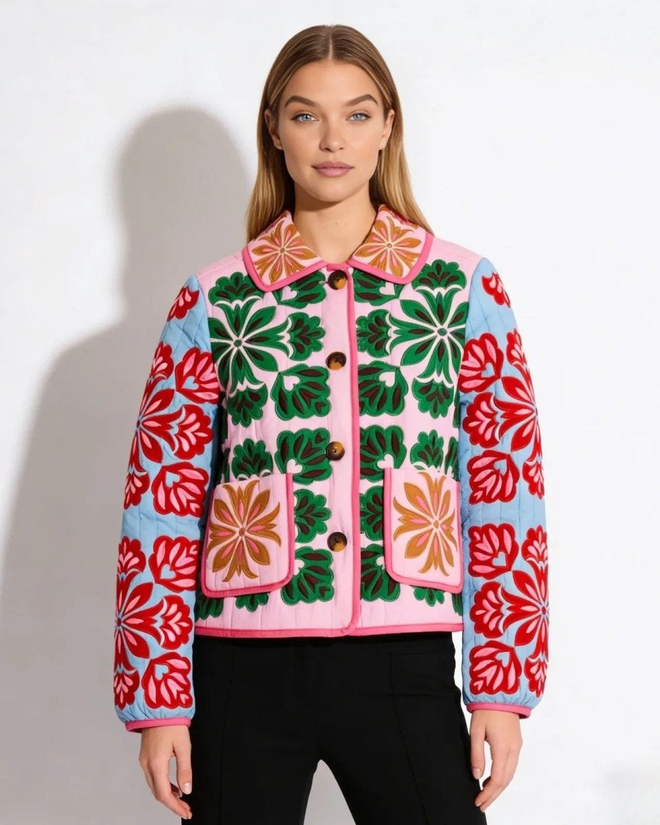 Model wearing the pink and green quilted jacket with intricate red and green floral embroidery, featuring a collar and patch pockets.