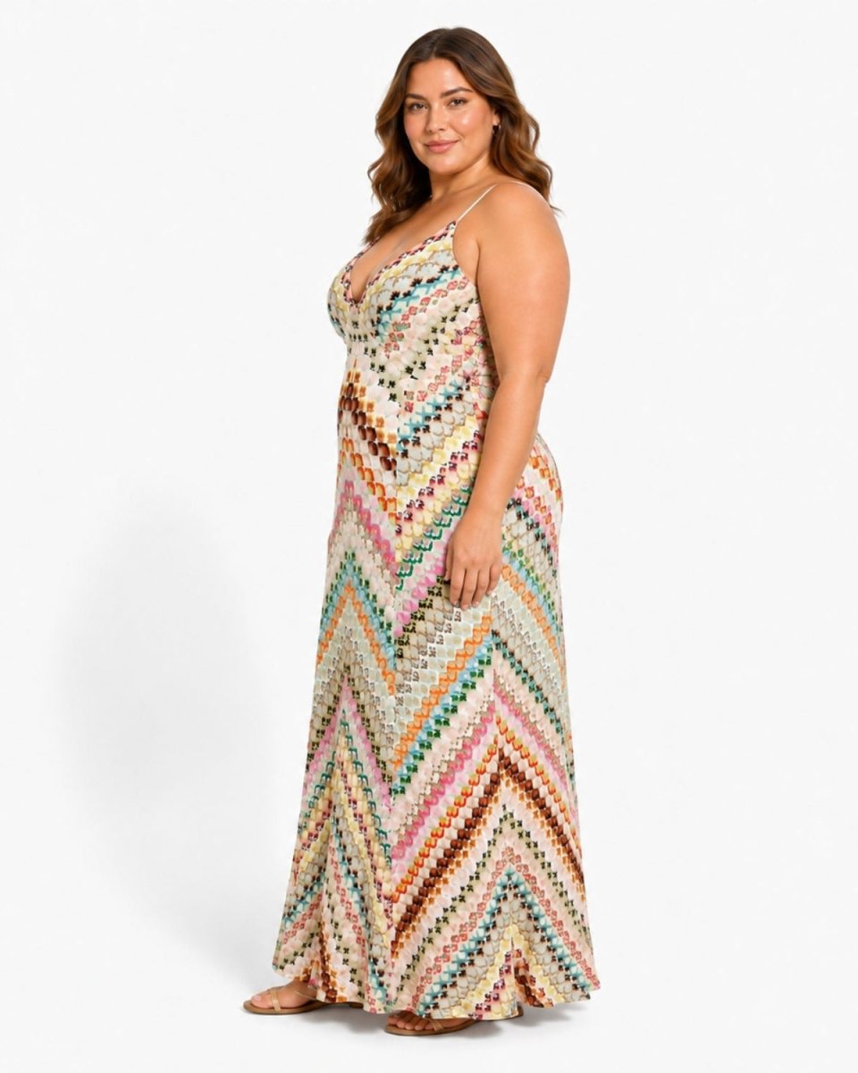A woman modeling a sleeveless maxi dress with a colorful chevron knit pattern on a light beige background, photographed against a plain white studio backdrop.