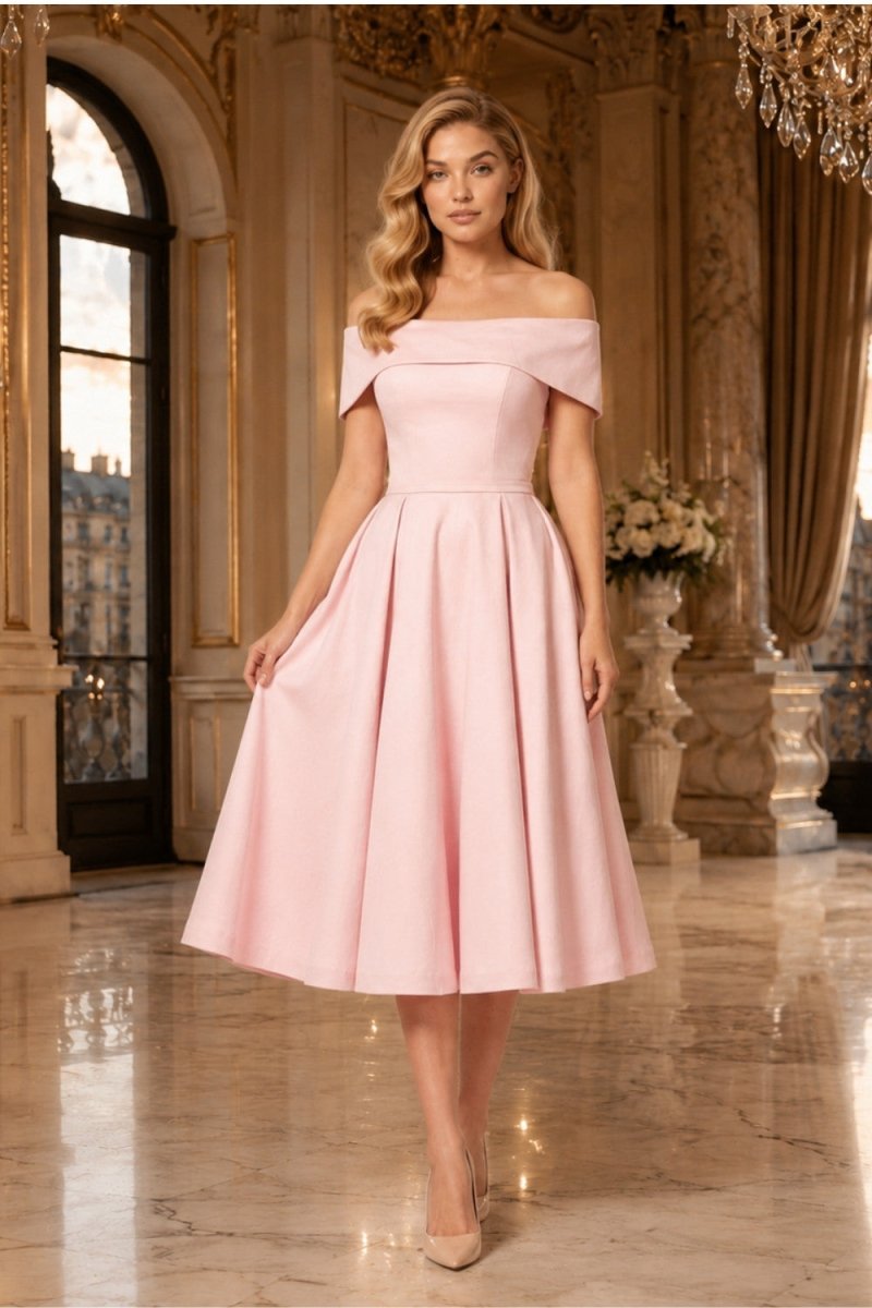 A woman models an off-the-shoulder pink midi dress with a structured bodice and flared skirt, standing in an elegant, ornate interior hall with marble floors and gold-toned columns.