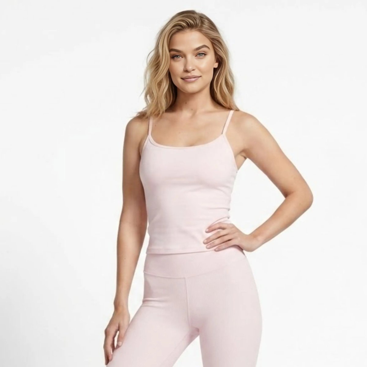 Woman wearing affordable luxury blush pink ribbed high waisted leggings and matching racerback tank top front view.