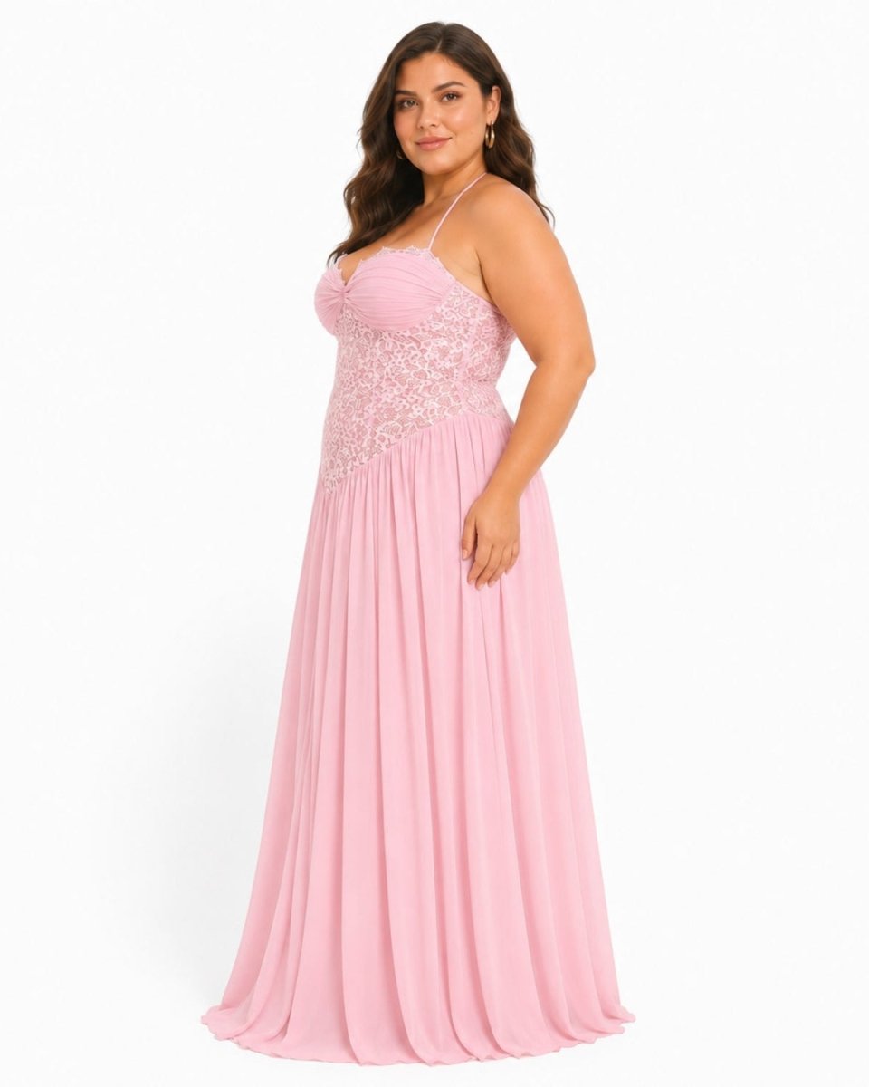 A woman modeling a floor-length light pink gown with thin straps, a lace-embroidered bodice, and a flowing chiffon skirt against a plain white studio background.