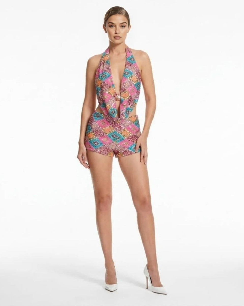 Woman wearing Kouvr pink sequin cutout halter romper with diamond pattern, tailored shorts, and deep plunge neckline.
