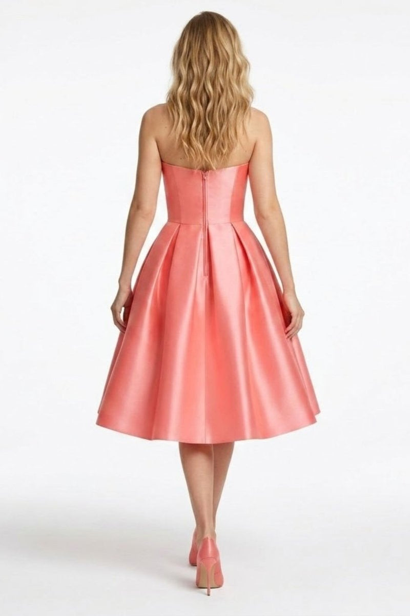 Back view of the strapless coral pink formal midi dress showing the hidden zipper and wide pleated skirt drape.