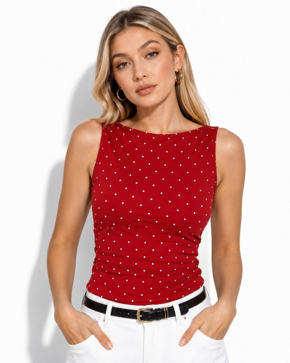 Woman wearing crimson red polka dot top with ruched detailing, perfectly paired with white denim and a black belt.