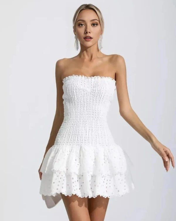 Woman wearing a white strapless dress against a plain background