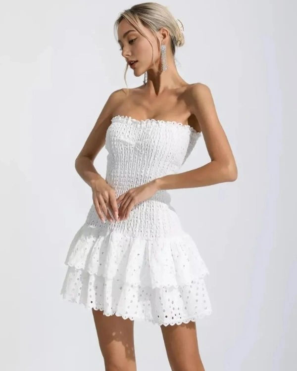 Woman wearing a white strapless dress against a plain background