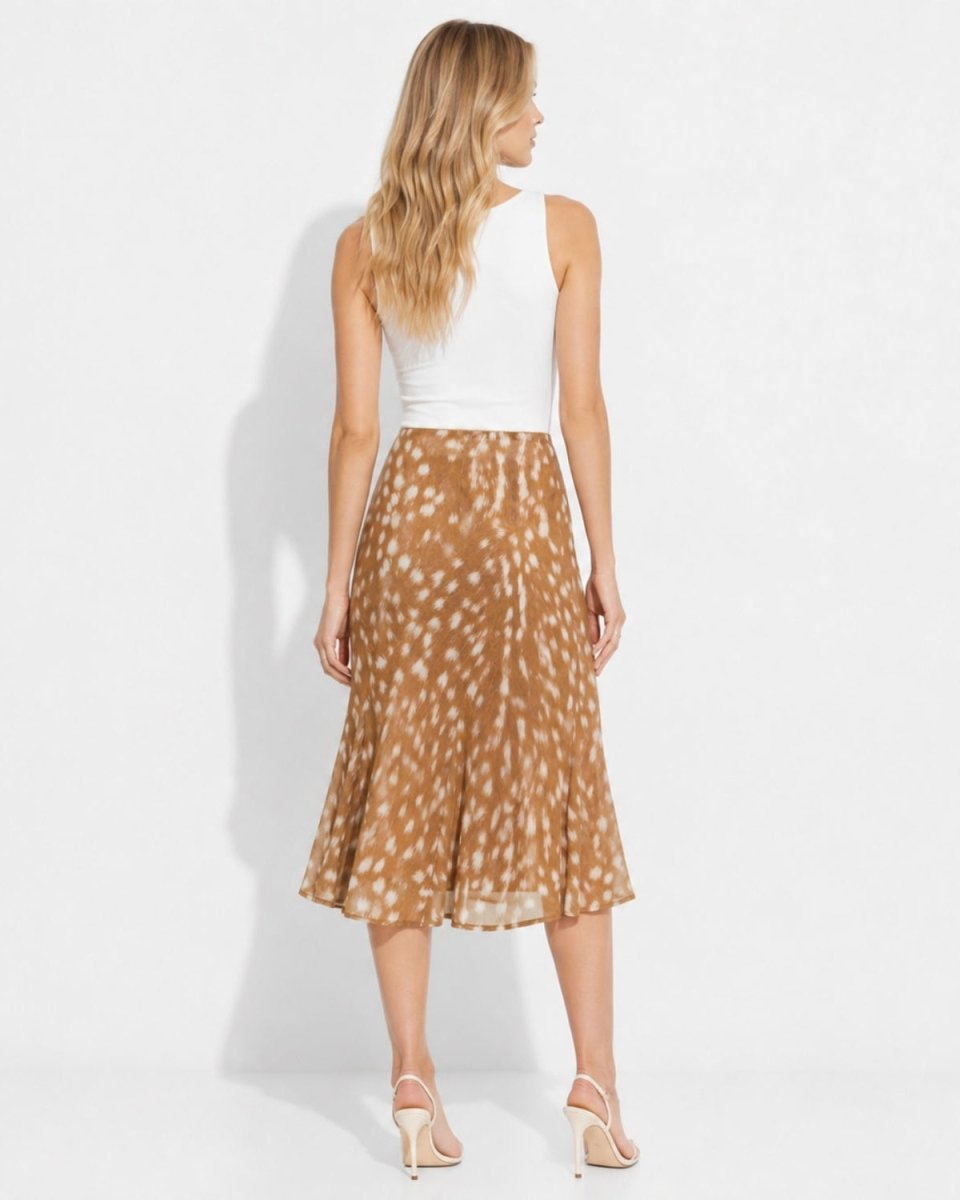 A woman shown from the back wearing a sleeveless white top and a brown midi skirt with a white spotted animal-like print, standing against a plain white studio background.