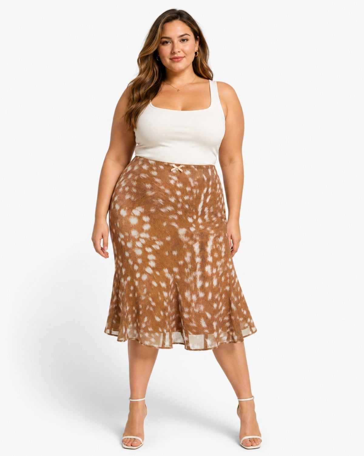 A woman modeling a brown and white tie-dye patterned midi skirt with a white ribbed tank top, standing against a light gray studio background.