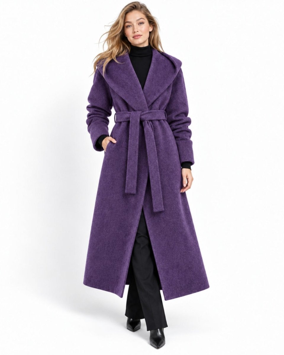 Front view of a woman wearing a luxury amethyst purple long wrap coat with an oversized hood and tie belt styled over black trousers.