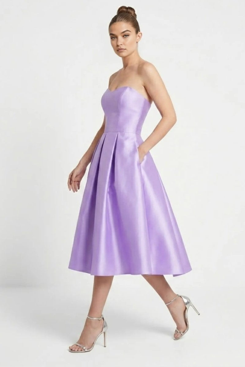 Side angle of the Fenlo Form purple satin A-line midi dress showcasing functional side pockets and a structured sweetheart neckline.
