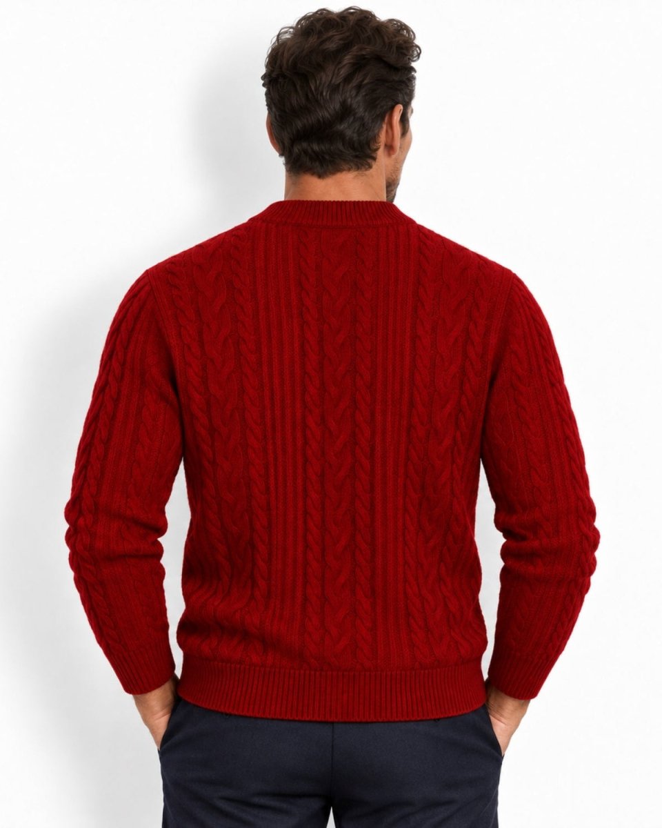 A man viewed from behind wearing a red cable-knit sweater and dark navy trousers, standing against a plain white studio background.