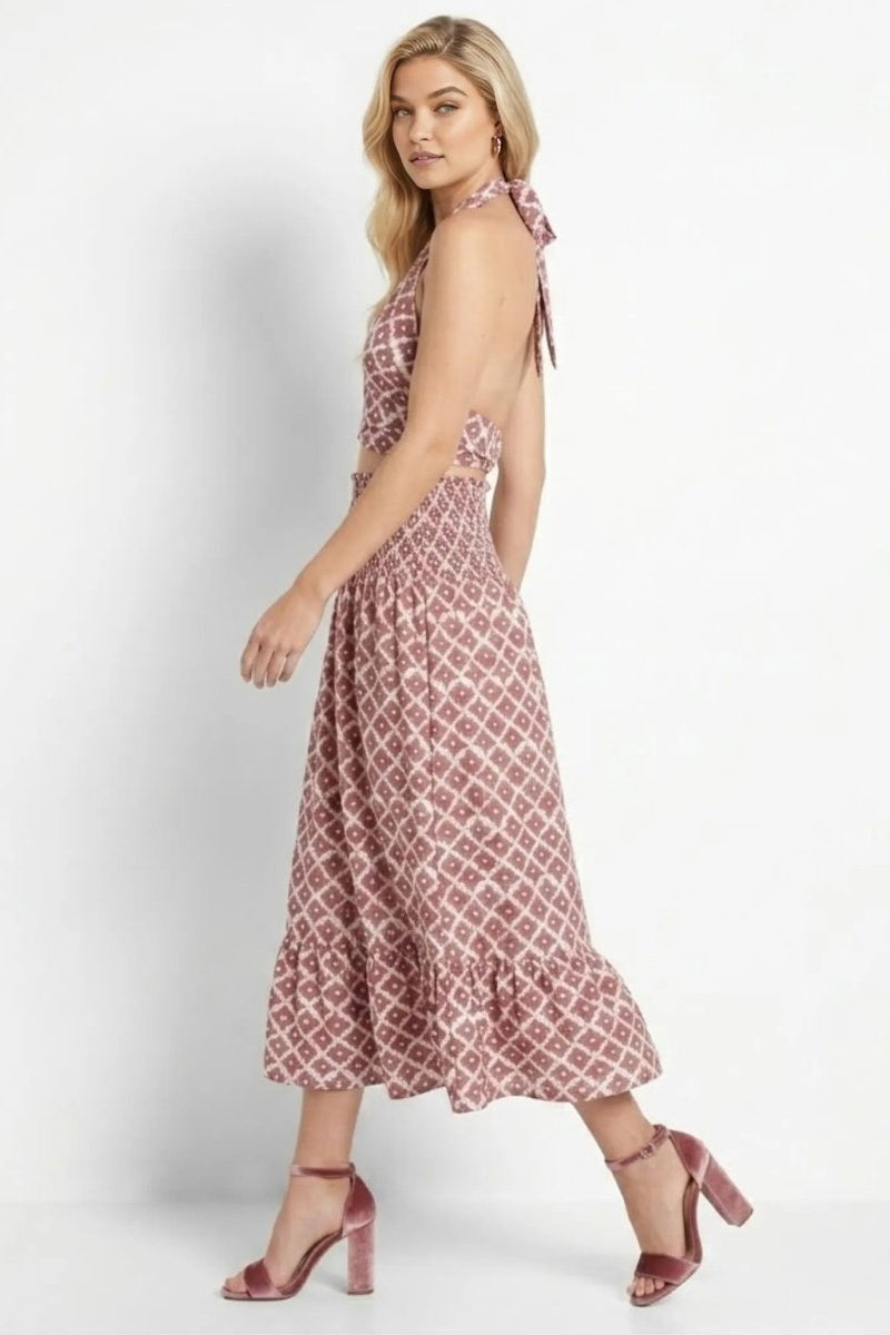 Side profile of woman walking in Fenlo Form red vacation matching skirt set showing back tie and open back detail.