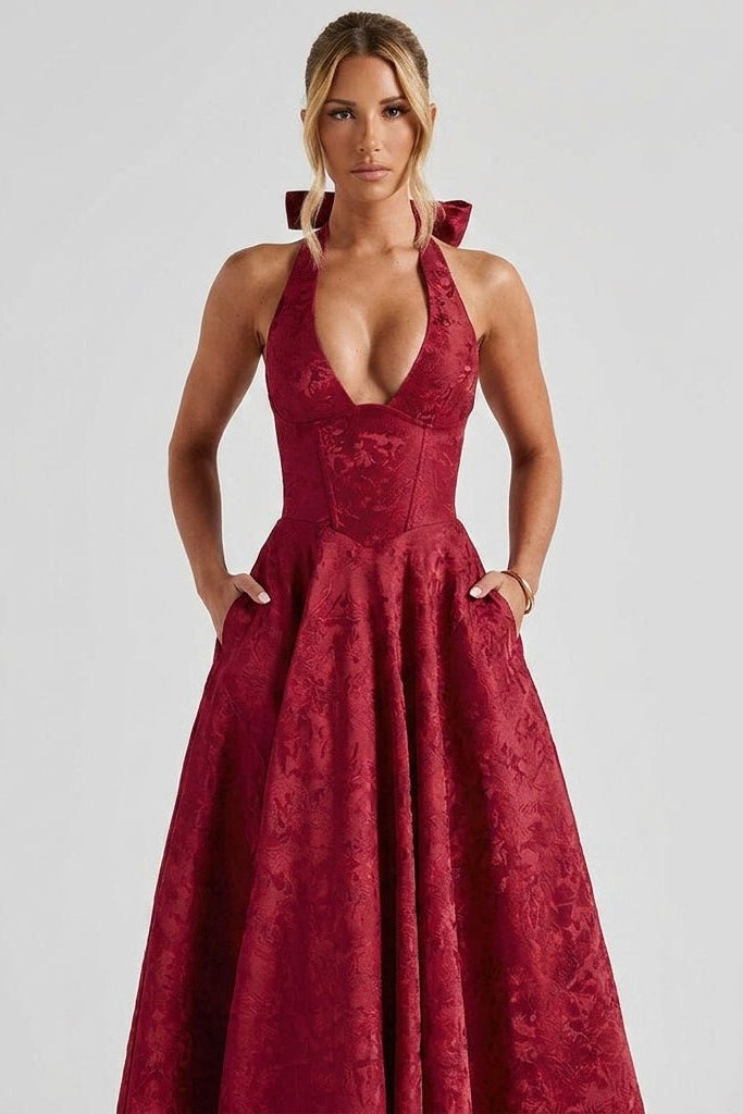 Woman modeling the Kouvr burgundy floral textured A-line midi dress with her hands in the functional hidden side pockets.