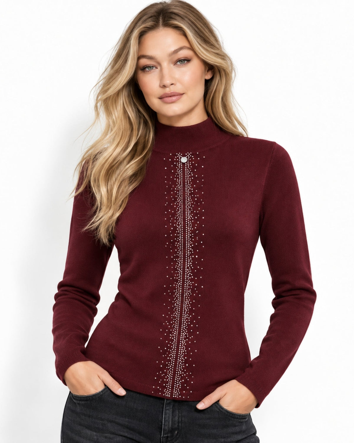 A woman modeling a fitted long-sleeve mock neck sweater in burgundy with a vertical line of silver rhinestone embellishments down the center front, paired with dark jeans against a plain white studio background.
