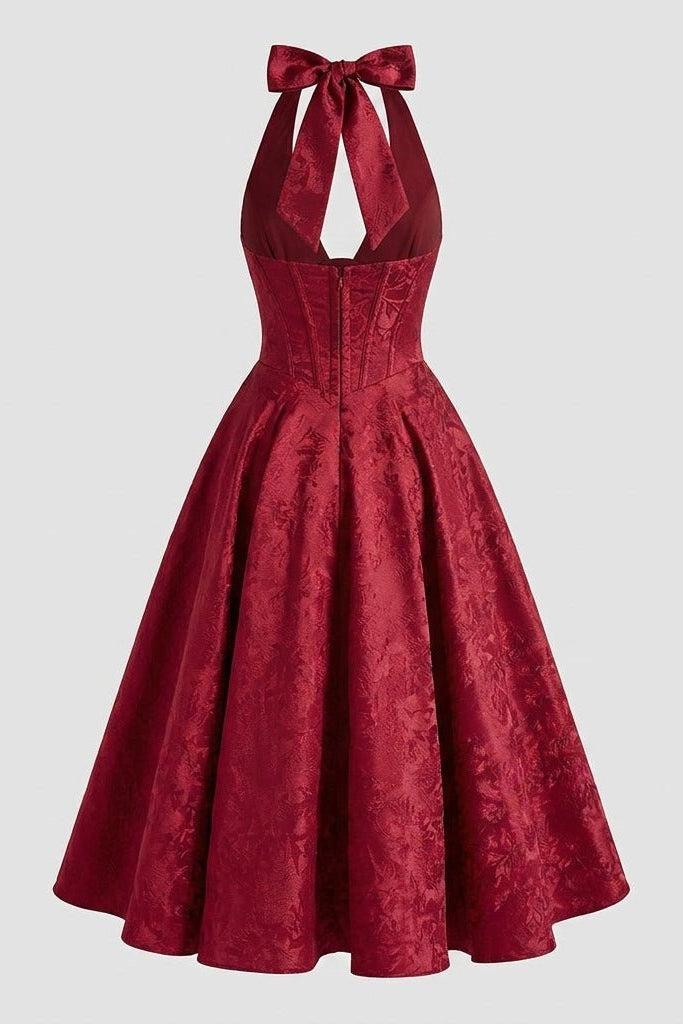 Flat lay back view of the Kouvr deep red floral jacquard midi dress highlighting the rear open back cutout, large tie bow, and invisible zipper closure.