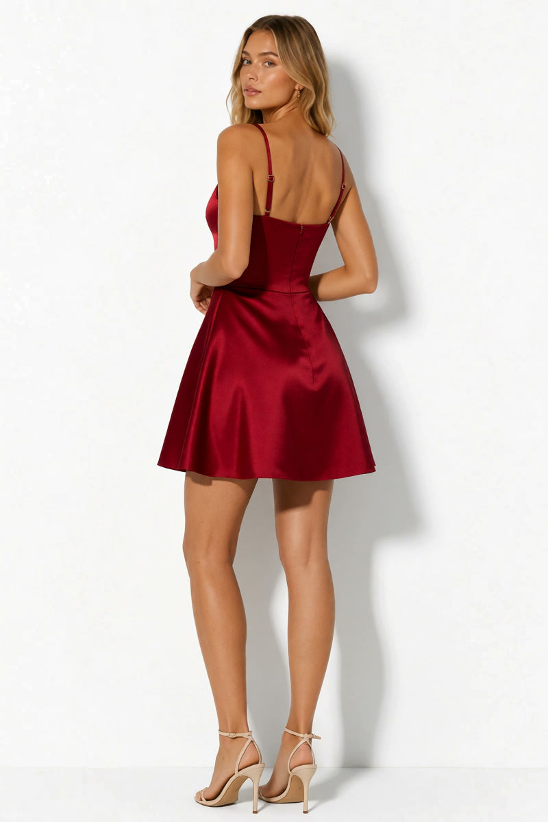 A woman modeling a short satin mini dress in deep burgundy red, shown from the back against a white studio background.