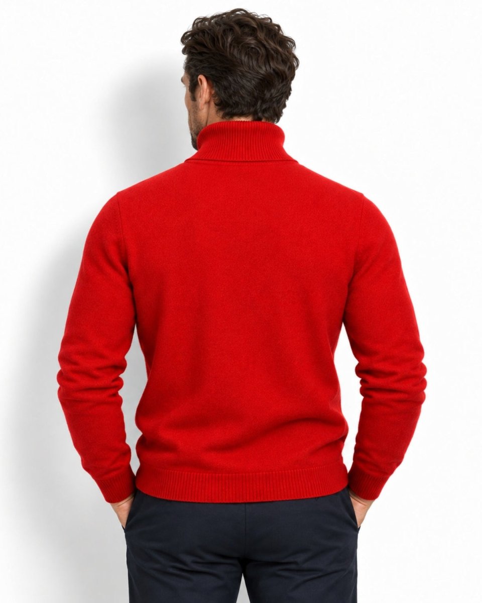 A man viewed from the back wearing a bright red knit turtleneck sweater and dark navy trousers, standing against a clean white studio background.