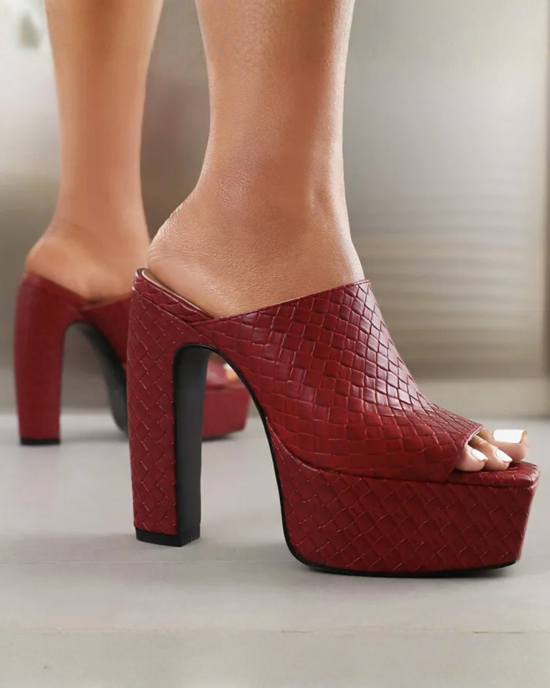Red woven-texture platform mule heels with high block heels, shown on a model's feet in a close-up shot.