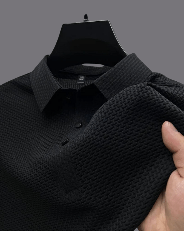 Black textured shirt held by a hand against a gray background