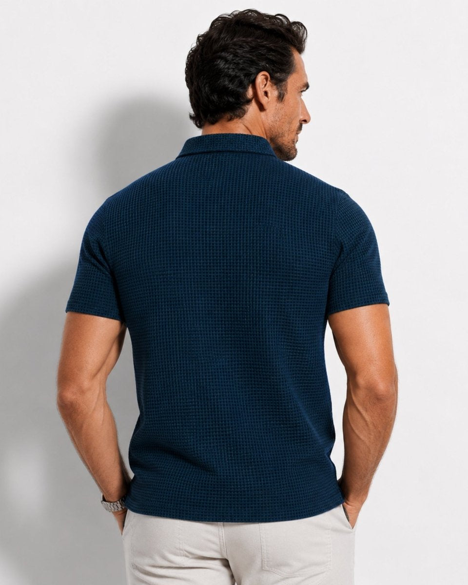 Man wearing a navy blue textured polo shirt against a light gray background