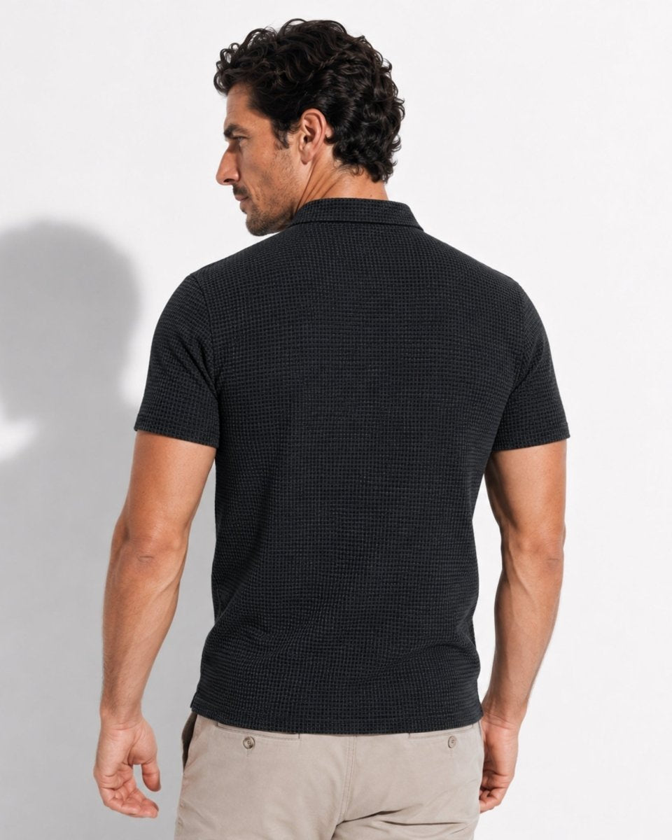 Man wearing a black patterned polo shirt against a white background