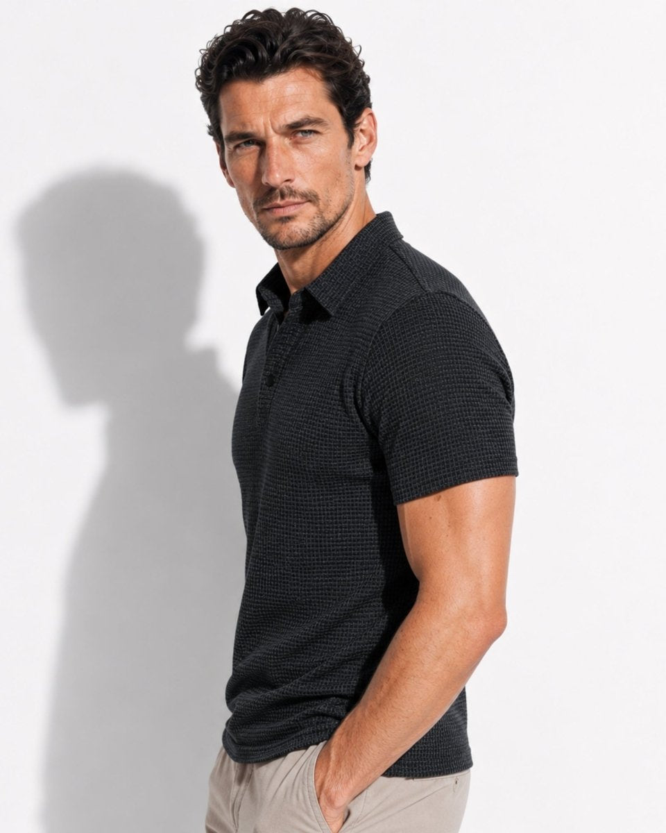 Man wearing a black patterned polo shirt against a white background